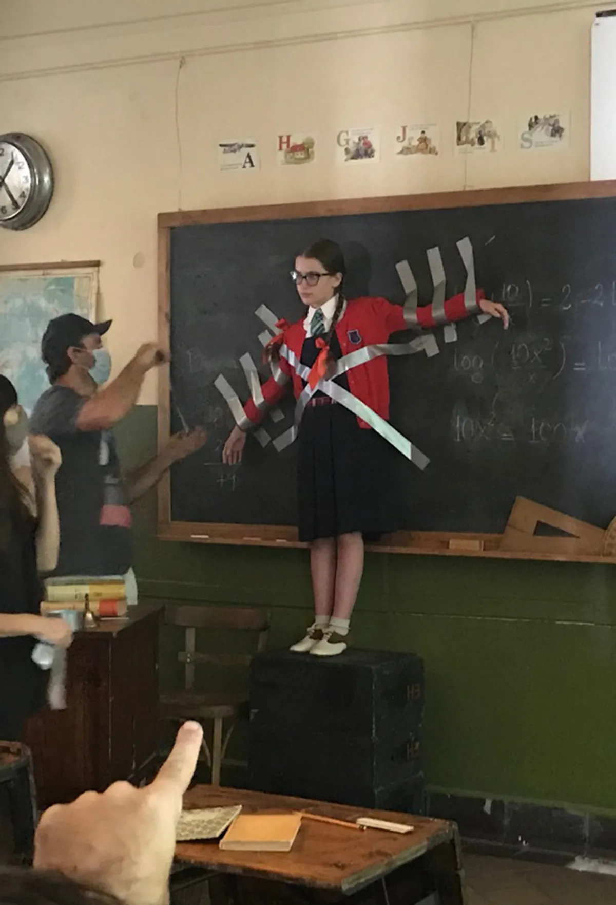 Behind the scenes: an actor taped to a blackboard